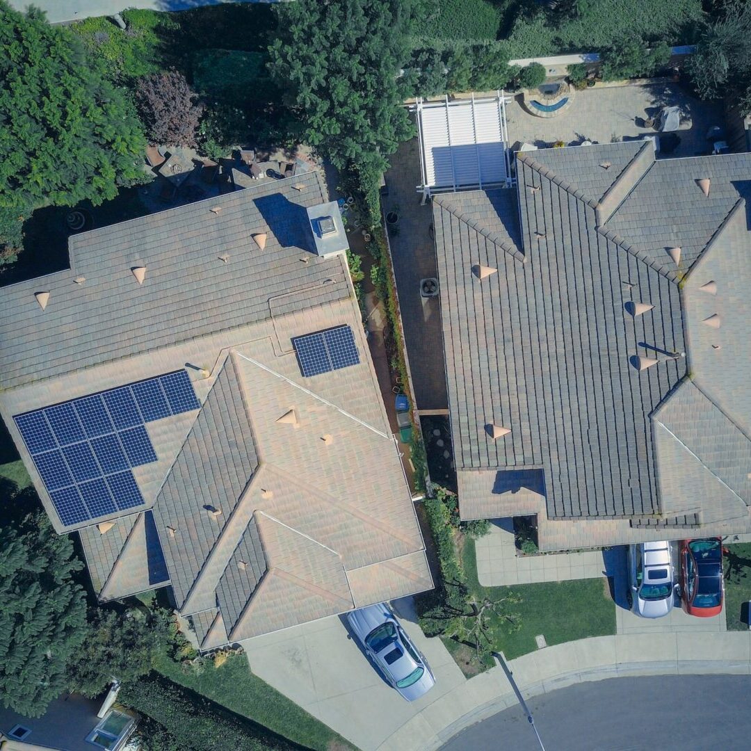 Aerial view of two suburban homes with solar panels on the roofs.